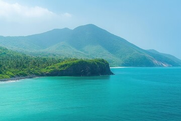 turquoise sea meeting a rocky green headland and lush coastal forest with rolling blue-green mountains under a clear sky, a tranquil tropical seascape