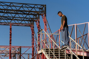 Man carefully walks on high stair rail in outdoor metal parkour zone, demonstrating control, coordination, and confidence in movement. Precision in urban acrobatic movement. Parkour performance. Momen