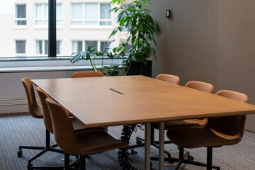 Fototapeta premium Long wooden boardroom table in office large glass windows