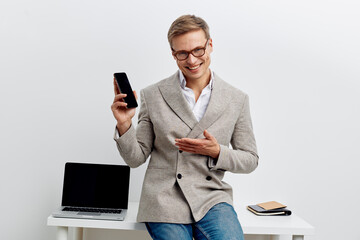 smiling man holding smartphone wearing glasses casual jacket sitting near laptop digital nomad remote work concept communication technology