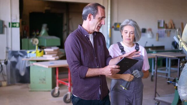 Factory workers discussing project on tablet computer