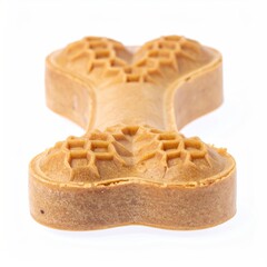 Dog treat shaped like a bone.  Close-up, light tan color.  Etched pattern.  Isolated on white