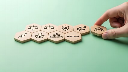 A hand arranging wooden hexagonal tiles with various symbols on a green background