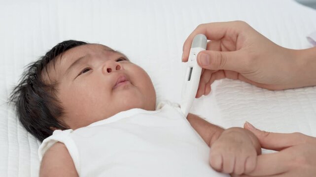 Pediatrician appointment, mother hold infant baby. Doctor write notes after clinic examination explain health diagnosis and medical support, disease prevention and vaccine. Doctor use thermometer
