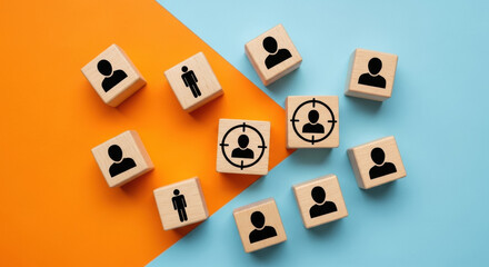 Scattered wooden cubes with black human silhouettes and one with a target sign on a vibrant split orange and blue surface symbolizing business targeting and customer selection.