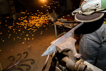 Blacksmith, knife sharpening, sparks, metal. Forging molten metal. Making knives.forge workshop