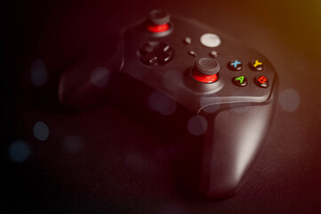 Close-up of a black wireless game controller on a dark surface with glowing buttons, symbolizing modern gaming, digital entertainment, interactive play, and competitive esports.
