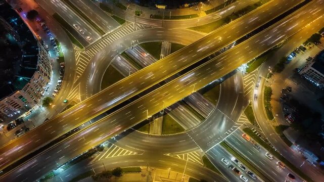 Night aerial view of a tangled multi level highway interchange with glowing city lights.