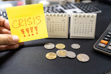 Hand holding sticky note with CRISIS text and 2026 calendar for economic warning concept. upcoming financial global crisis, economic downturn, inflation alerts.