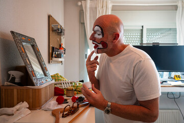 Performer applying clown makeup in front of mirror