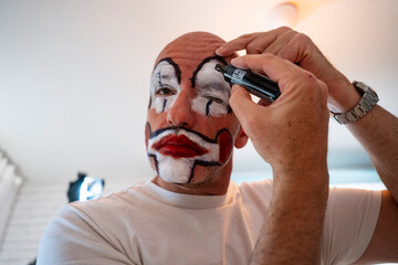 Man applying clown makeup before performance