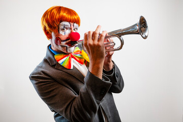 Clown in red wig playing a trumpet instrument