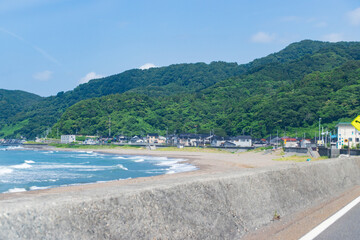 Coastal Village Landscape with Sea Wall and Rolling Green Hills in Japan