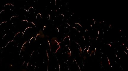 Spectacular golden and red fireworks explode against the deep black night sky celebrating a festive holiday occasion