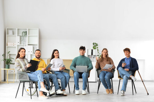 Young man in wheelchair with applicants waiting for job interview at office