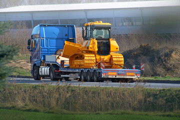 Heavy machinery truck transports yellow construction loader © AlexGo