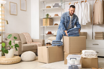 Young man with folded jeans and wardrobe boxes in dressing room