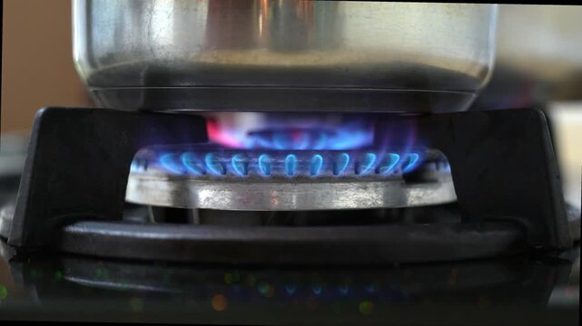A burning Liquified Natural Gas LNG kitchen gas stove with a stainless steel pot