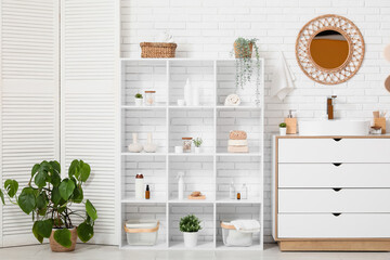 Interior of bathroom with shelf unit, folding screen and sink