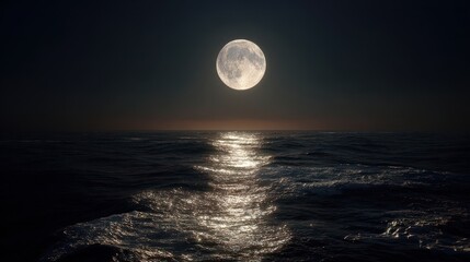 Bright moon shines over ocean water at night with reflections on the surface creating a calm view