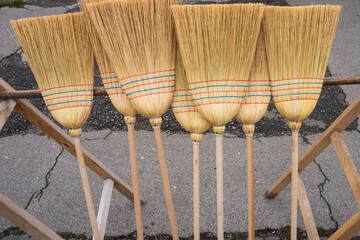 A pile of reed brooms. Cleaning tools made from natural materials arranged together.

