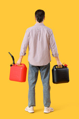 Young man with canisters on yellow background, back view
