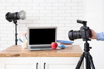 Female photographer with camera taking picture of workplace in studio, closeup