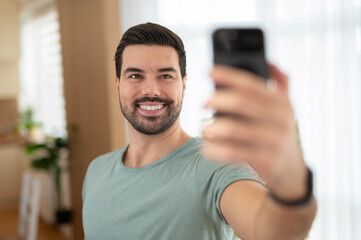 Man smiling while taking selfie with phone at home