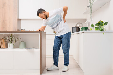 Young man suffering from back pain in kitchen