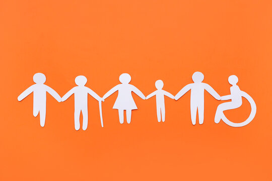 Paper human figures on orange background. Inclusion concept