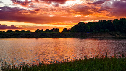 Naklejka premium Sunset on the cloudy river.