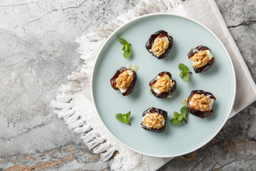 Sweet stuffed dates with cream cheese, walnuts and honey close-up in a plate on the table. Horizontal top view from above