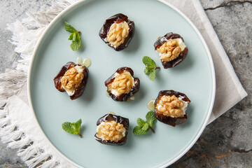 Honey walnut Cream Cheese Stuffed Dates in a porcelain plate closeup on the table. Horizontal top view from above