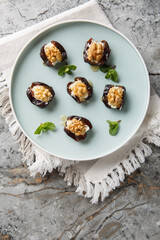 Arabic stuffed dates with cream cheese, walnuts and honey close-up in a plate on the table. Vertical top view from above