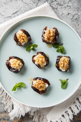 Close-up of dates stuffed with cream cheese, walnuts and honey in a plate on the table. Vertical top view from above