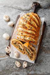 Vegetarian mushroom Wellington with onion, garlic and spinach closeup on the wooden board on the table. Vertical top view from above