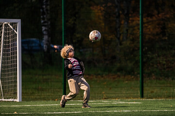 Boys play football in open stadium  with artificial lighting.