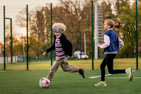 Children play football on an outdoor stadium with artificial turf.