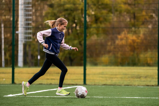 Young caucasian girl playing soccer on outdoor artificial grass field