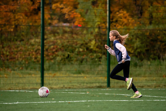 Young caucasian girl playing soccer on outdoor artificial grass field