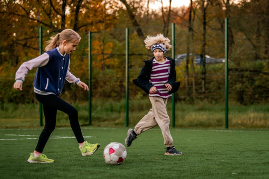 Children play football on an outdoor stadium with artificial turf.
