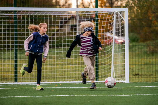 Children play football on an outdoor stadium with artificial turf.