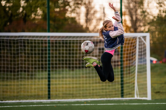 girl jongling soccer ball on field at autumn day.