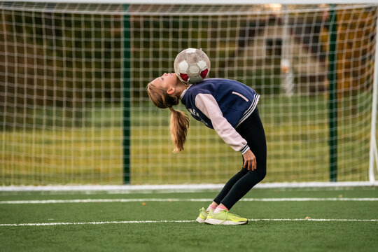 girl jongling soccer ball on field at autumn day.