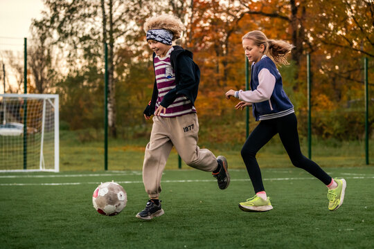 Children play football on an outdoor stadium with artificial turf.