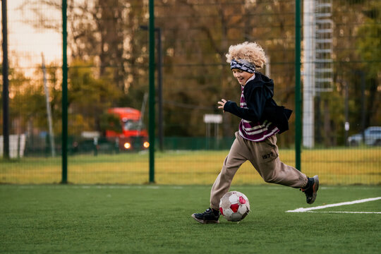 Young boy playing soccer, kicking ball on green field.