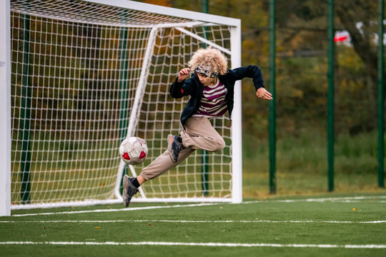 boy plays street football at an outdoor stadium.