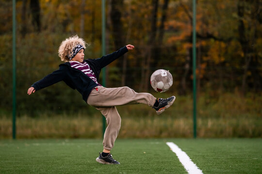 boy plays street football at an outdoor stadium.