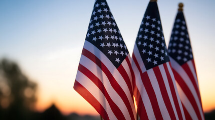 Three flags stand tall against a warm sunset. Stripes of red and white contrast against a blue sky, evoking a sense of patriotism and national pride in outdoor setting.