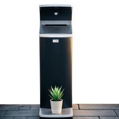A modern black vending machine stands on a brick floor with a small potted plant beside it.